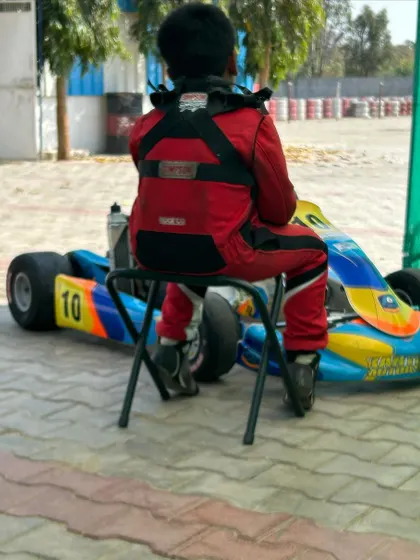 A young driver waiting by his kart.