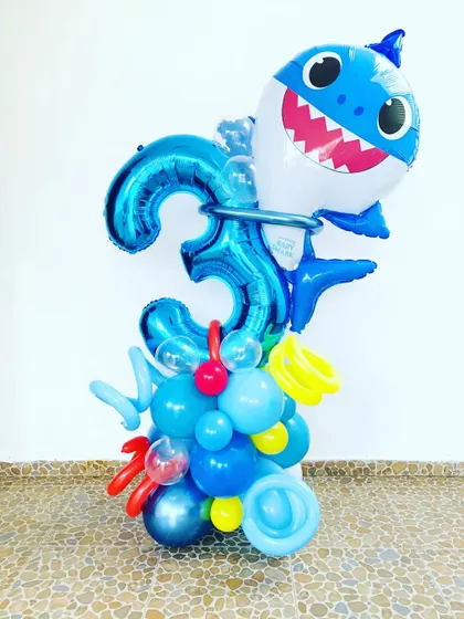 A fun Baby Shark balloon bouquet. This arrangement features a large Baby Shark foil balloon on top of a blue balloon pillar with a number '3' foil balloon.