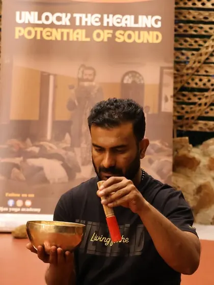 A student learns the proper technique for playing a singing bowl to produce a pure, sustained tone.
