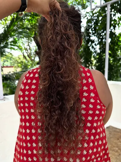 Holding up the curls to show the length and the beautiful, springy texture we achieved with this corrective cut and color.