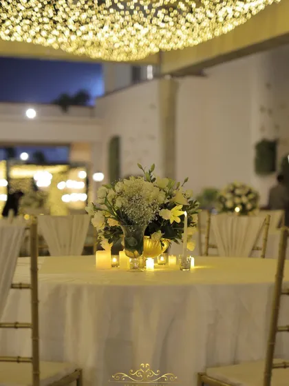 A close-up of a candlelit centerpiece with white flowers. The soft glow adds to the romantic and intimate atmosphere of the evening.