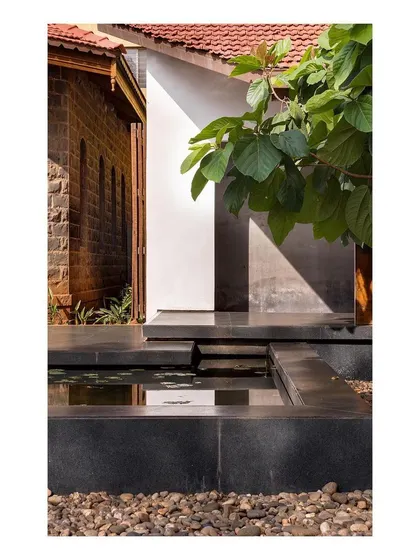 A close-up showing the material details of the museum's landscape. The contrast between the rough stone of the original building, the smooth new walkways, and the water creates a rich textural experience.