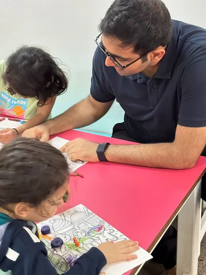 A father helps his child with a coloring activity during our extended Father's Day celebration. These moments of connection between parents and children within the school environment are incredibly valuable.