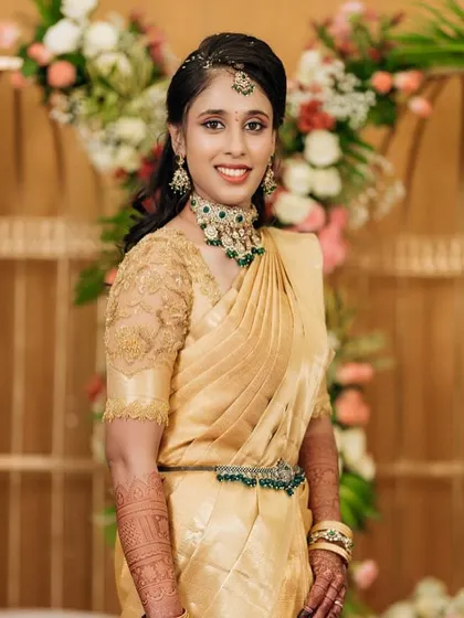 This bride looks absolutely stunning in her gold Kanchivaram saree for her engagement. The custom-designed blouse with delicate embroidery adds a touch of elegance to her look.