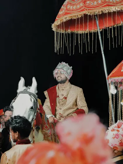 The groom's grand entrance on a white horse, complete with a traditional umbrella. This shot captures the excitement and tradition of the baraat procession.