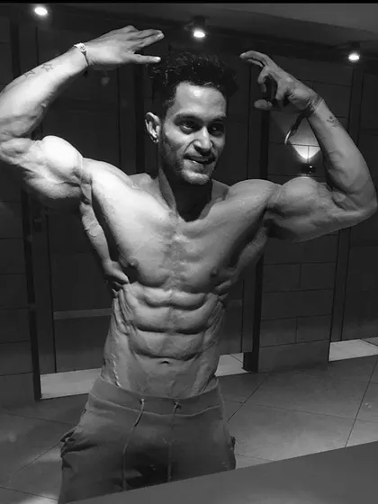 A black and white artistic shot highlighting muscle shadows and definition. This shows the physique as a sculpture, carved by dedication.