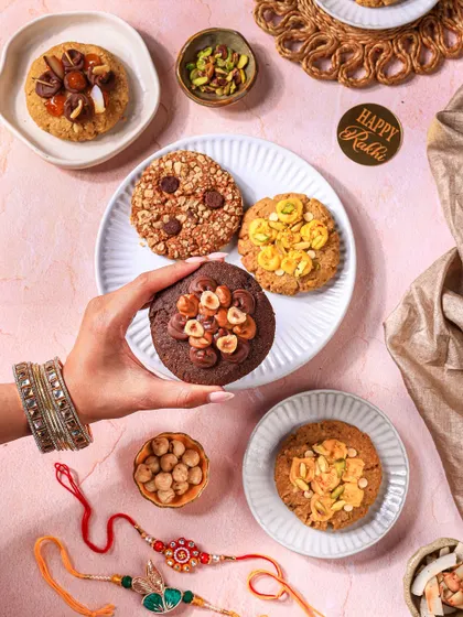 A lifestyle shot featuring a hand with traditional bangles holding up a cookie, connecting the product to the festive occasion.