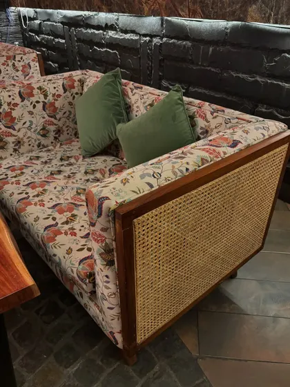 Adding some florals to the fall season. This unique sofa combines a sturdy teakwood frame with rattan cane detailing on the sides and is upholstered in a vibrant floral print, bringing a touch of bohemian charm to the space.