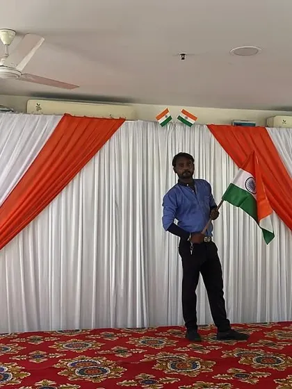 A simple and clean stage setup for an Independence Day event, with a tricolor fabric backdrop and a carpeted stage floor.