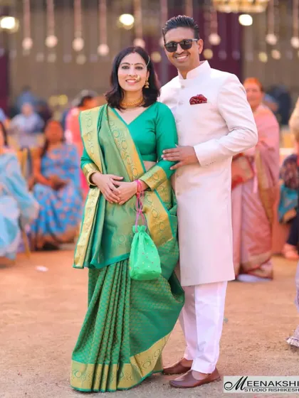 A beautifully dressed couple at a wedding event. Their elegant green and white traditional outfits stand out, and the photo captures a moment of posed grace amidst the celebration.