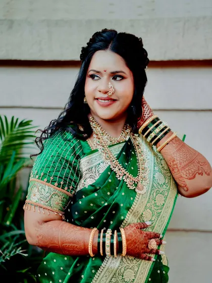 The rich green of her saree and the intricate gold jewelry are the perfect frame for her glowing makeup. This is a classic and regal Maharashtrian bridal look.