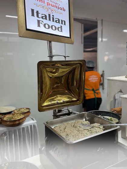 Our live Italian food station, where chefs prepare classic dishes like pasta. The empty chafing dish signifies the popularity of this counter, with guests eagerly enjoying the food as soon as it's made.