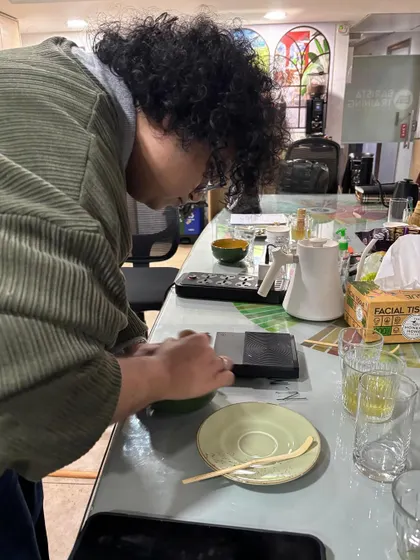 A student carefully weighing matcha powder. Precision is just as important in making matcha as it is in brewing coffee.