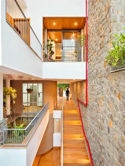 This view captures the essence of the People Tree House, with its multi-level design creating a dialogue between spaces. A wooden walkway crosses over an indoor water body, connecting to a stone feature wall, demonstrating how I blend natural textures and biophilic design to create a home that feels alive.