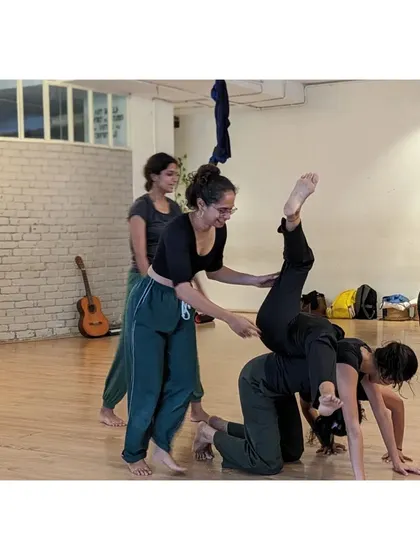 An instructor assists students in a partner acrobatics pose, ensuring safety and proper technique during an X-Sense session.