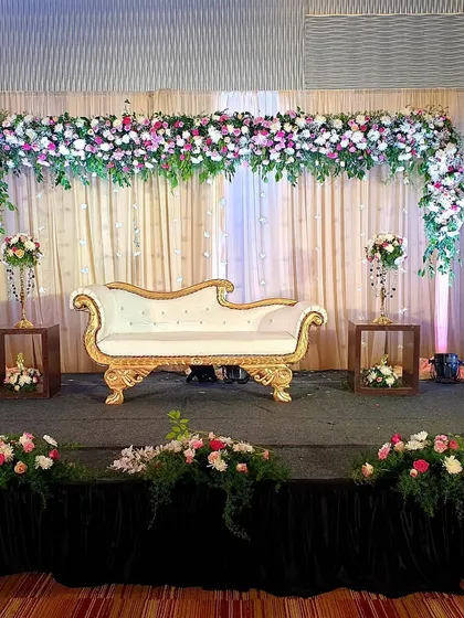 A full view of an elegant floral arch stage I created for a wedding. The design uses a soft color palette of pink and white, with simple fabric draping and minimalist side tables to keep the focus on the floral centerpiece.