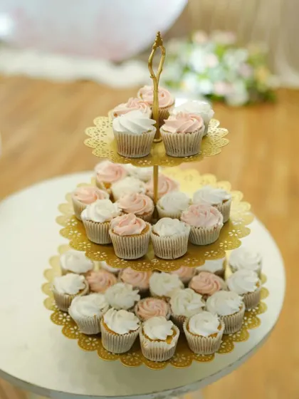 A closer look at the peach and white cupcakes from the baptism dessert table. Displayed on a three-tier stand, they create an elegant and inviting treat for guests. This colour combination is so soft and pretty for a baby's celebration.