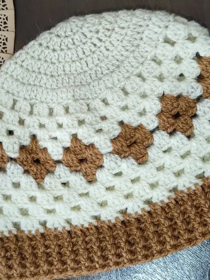 The finished Diamond Granny hat, featuring a band of diamond motifs created with brown yarn against a cream background. The brim is ribbed for a snug fit.