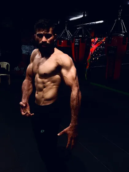 A moment of reflection after a hard session. One of our fighters posing in the gym, showing the chiseled physique that comes from discipline and hard work.