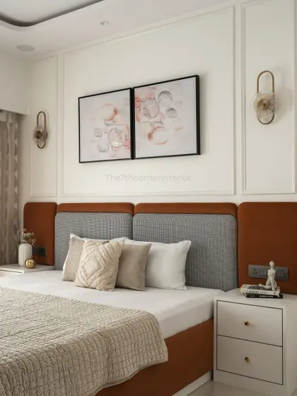 The master bedroom in the 'Elysian Enclave' project features a long, statement headboard in a vibrant pop of orange and grey fabric, injecting energy and vitality into the space.