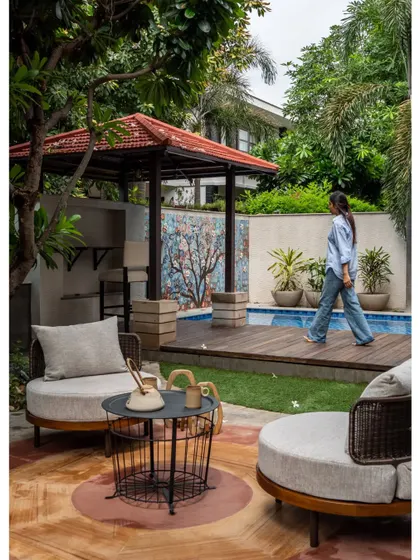A view of the backyard, featuring a new pool, a wooden deck, and a covered gazebo with a bar. The space is designed for relaxation and entertainment, with a beautiful mosaic art piece as a focal point.