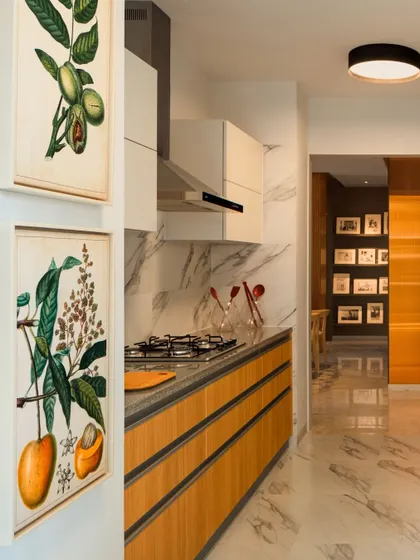 The kitchen is the heart of the home, and we design it to be both beautiful and highly functional. This kitchen features a blend of warm wood, marble-finish backsplash, and sleek cabinetry, with botanical art adding a personal touch. Every layout is planned for ergonomic ease, making daily rituals feel seamless and intuitive.