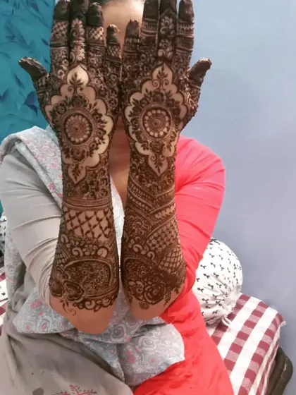 Another view of Misba's celebratory henna, showing the full arm design and the matching simple patterns on her feet.
