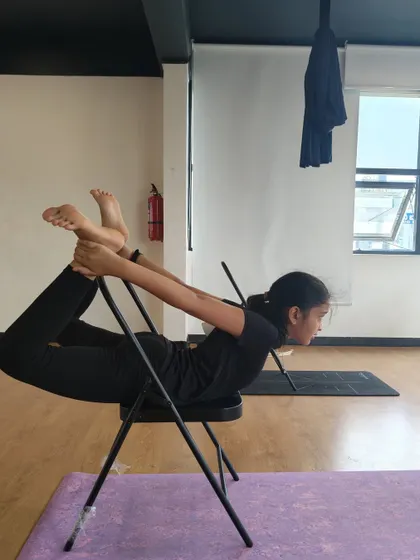 Using a chair to deepen the stretch in Dhanurasana, or Bow Pose. Props are fantastic tools for helping kids safely explore the full range of their bodies.