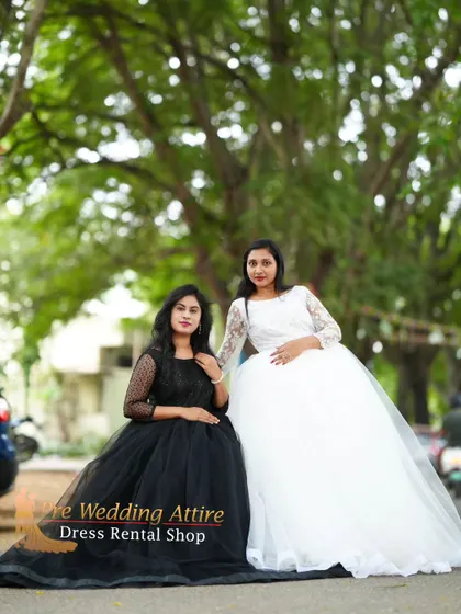 A seated portrait of two women in black and white ball gowns, showing the beautiful volume and drape of the skirts.