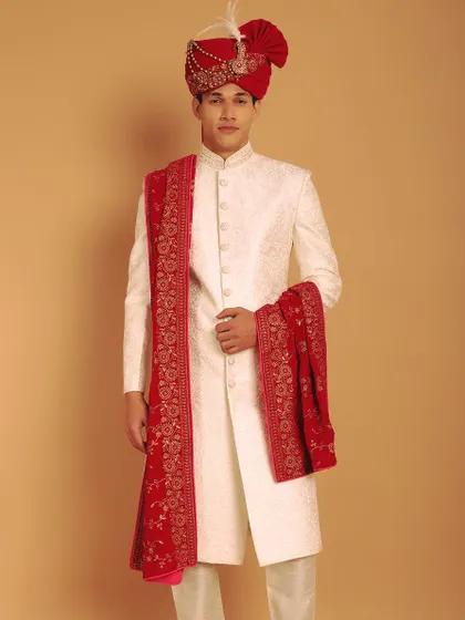 For a classic and powerful groom's look, I pair an ivory self-embroidered sherwani with a rich, red velvet stole. This combination of colors and textures creates a timeless and royal aesthetic, perfect for a grand wedding ceremony.