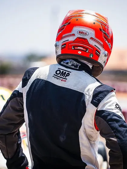 A driver stands ready by his kart, a picture of focus and determination before the final round of the Meritus Cup.