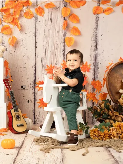 The birthday boy enjoying a ride on the rocking horse in his cozy autumn setup.