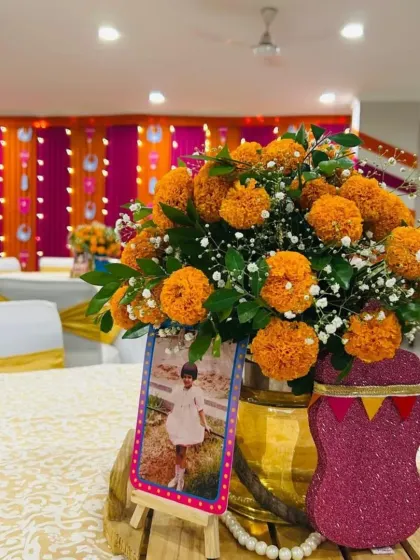 A traditional table centerpiece featuring a brass pot filled with bright orange marigolds. We added a personal touch with a childhood photo of the mom-to-be, making the decor more meaningful.