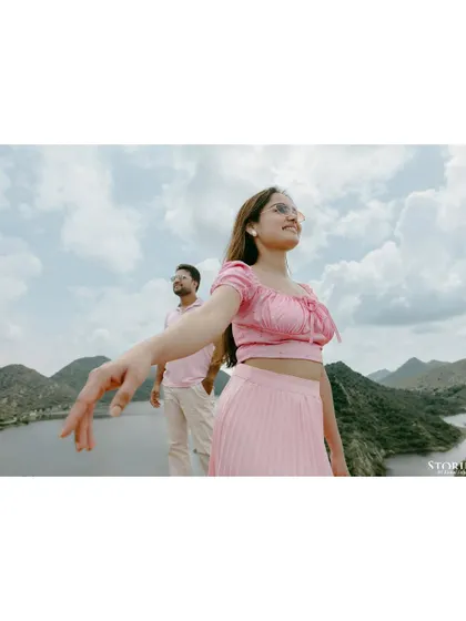 A beautiful, joyful portrait with the stunning Aravalli hills and lakes of Udaipur in the background. The bride's pose invites the viewer into her world of happiness.