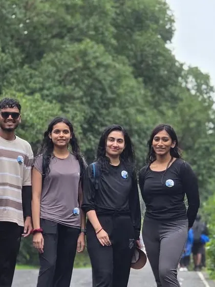 A group of friends posing for a photo on the road leading to the Kurinjal trek start point, with lush greenery all around.