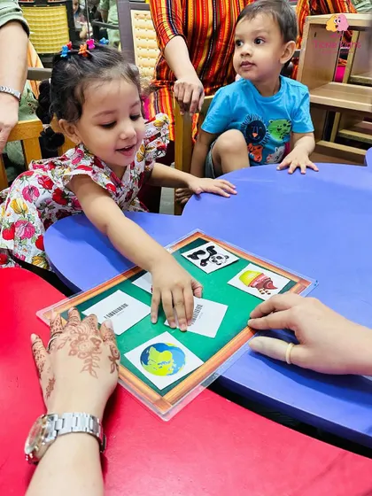 A girl proudly matches a picture card, her smile showing her sense of accomplishment. Our games are designed to be fun while reinforcing important concepts like vocabulary and object recognition.