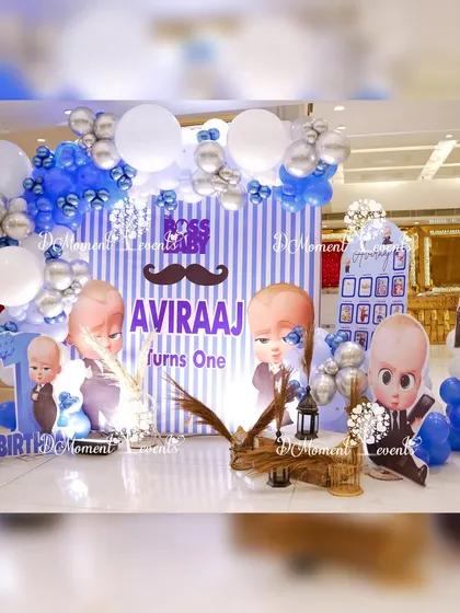 A fun and stylish photo booth for a "Boss Baby" party, with a striped backdrop, character cutouts, and themed balloon arrangements.