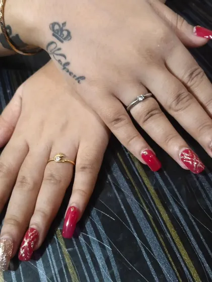 This is a powerful and glamorous nail set, perfect for a wedding reception or a big party. I used long, square-shaped extensions with a deep red polish and full-coverage gold glitter on the accent nails. The tattoo on her hand adds to the cool vibe.