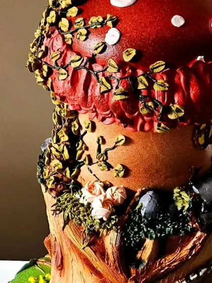 A close-up of the top of the mushroom house cake. You can see the texture of the mushroom cap and the delicate, trailing vines, all piped with whipped cream.