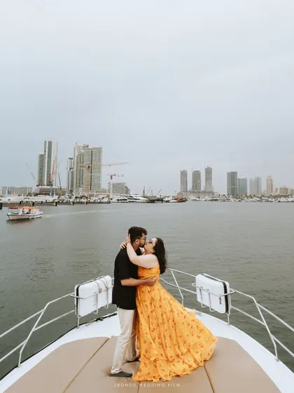 A romantic kiss on the bow of the yacht, with the expansive water and distant Dubai skyline creating a breathtaking backdrop for this cinematic pre-wedding photograph.