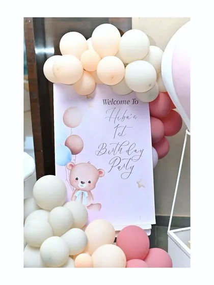 A sweet welcome sign for Heba's 1st birthday party, featuring a cute teddy bear and a soft pastel balloon garland.