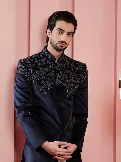 A deep navy velvet Indo-Western jacket with intricate tonal embroidery on the shoulders and chest. This piece exudes luxury and is perfect for a formal evening affair.