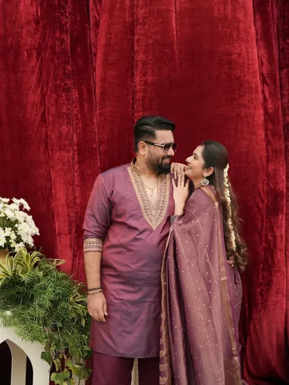 A sweet, candid moment between Tharun and Sonal. The coordinated wine-colored outfits look so rich and beautiful against the red velvet backdrop.