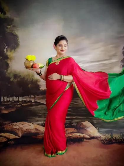 A graceful portrait of a mom-to-be in a traditional red and green saree. The flowing fabric and her serene expression create a timeless image.