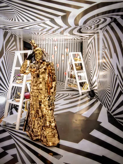 An illusion tunnel with black-and-white optical patterns created a disorienting and exciting entrance to the 'Cirque of Love' party, where a golden Mirror Man greeted guests.