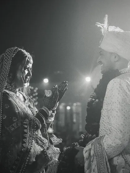 Another angle of a wedding ritual in black and white, focusing on the bride's actions and the dramatic lighting.