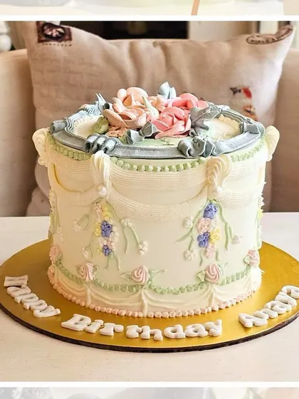A vintage-style cake with intricate Lambeth piping in pastel blue and pink, creating a classic and ornate design.