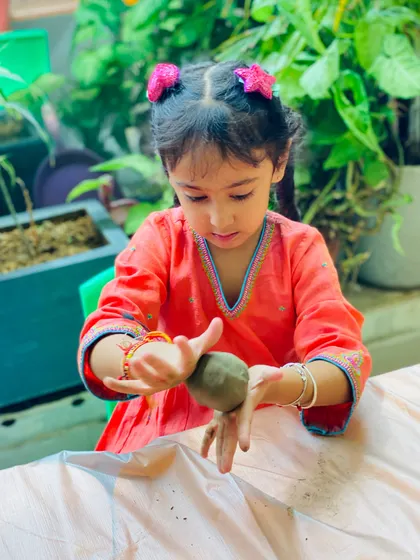 A duplicate of image 28, showing a young artist fully immersed in her craft. The tactile nature of clay is excellent for sensory development and creative expression.