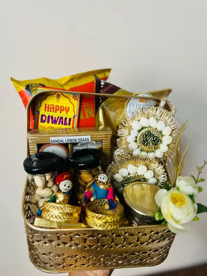 A beautiful Diwali basket filled with traditional Indian sweets, dry fruits, and decorative items, held up for a clear view.