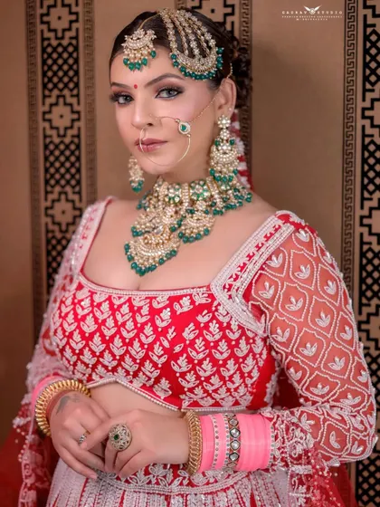A medium shot of the bride looking confidently at the camera. The composition balances her detailed outfit and jewellery with a clean, patterned background.